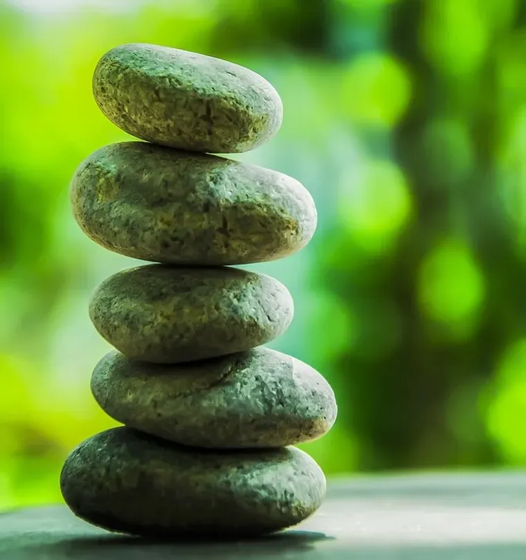 Chéile Wellbeing workplace wellbeing: a balanced stack of smooth stones against soft green foliage