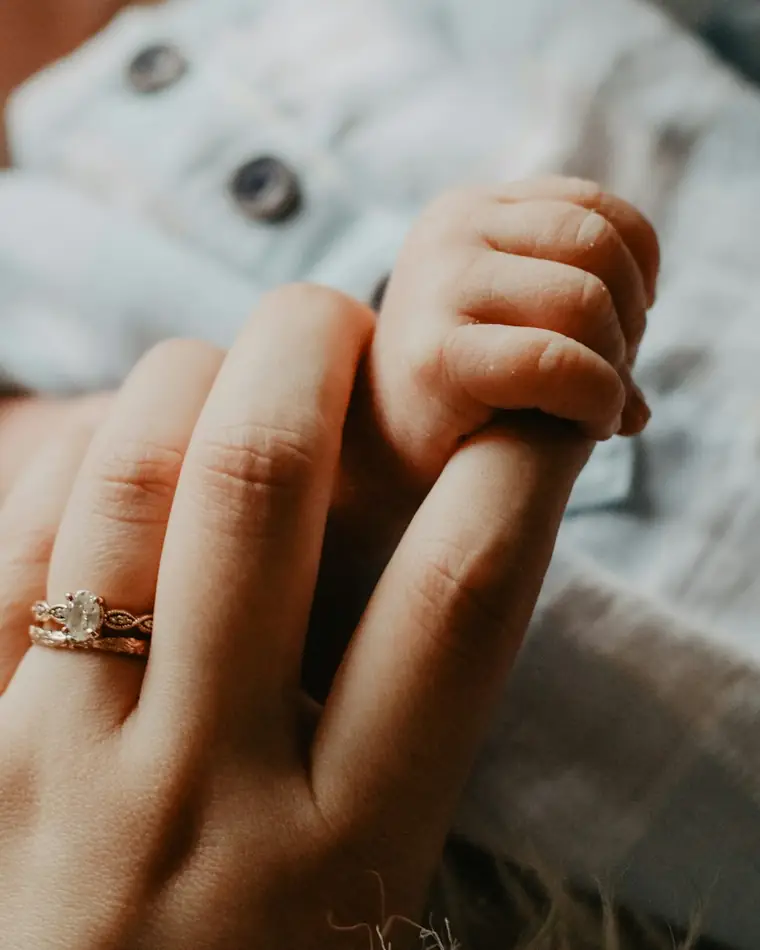 A baby holding a mother's finger